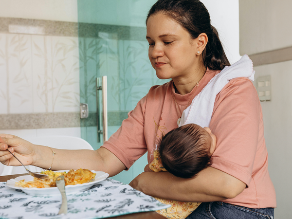 Mother holding baby while eating